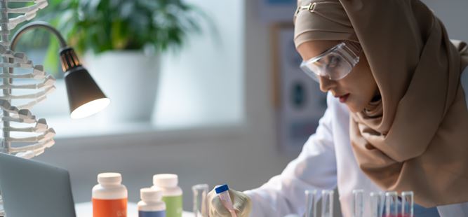 A young scientist wearing a headscarf and safety goggles working in a lab