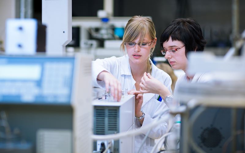 A photo of two young female scientists examining something carefully in a lab