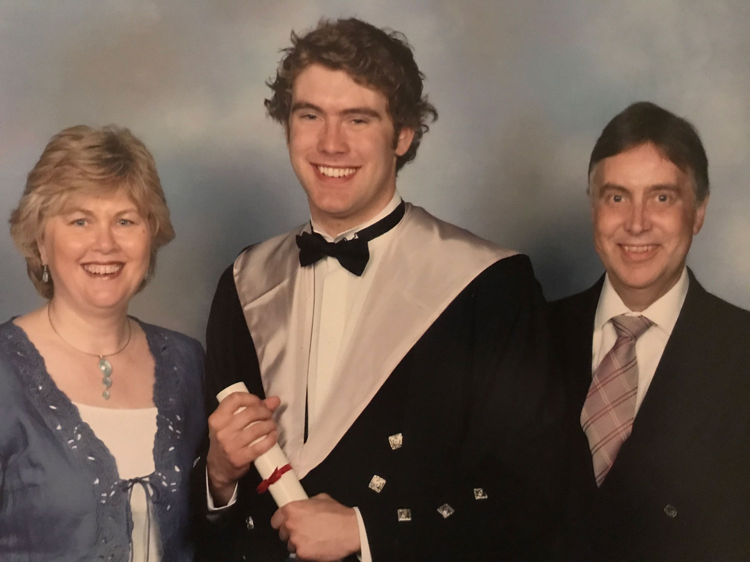 A photo of Adam and his parents at graduation