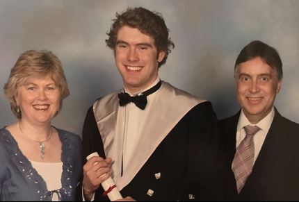 A photo of Adam and his parents at graduation