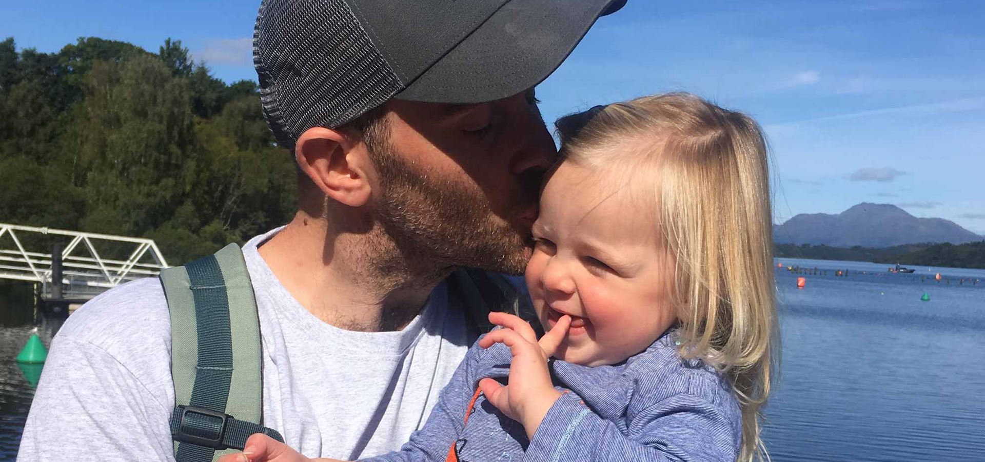 Adam holding his daughter Skye outside and kissing her on the cheek