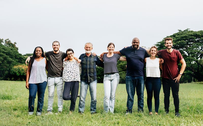Diverse group of people smiling together in a field