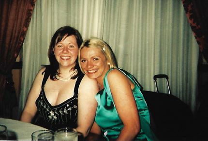 Cathrin and her friend Mairi sitting together and smiling at a table at a formal event