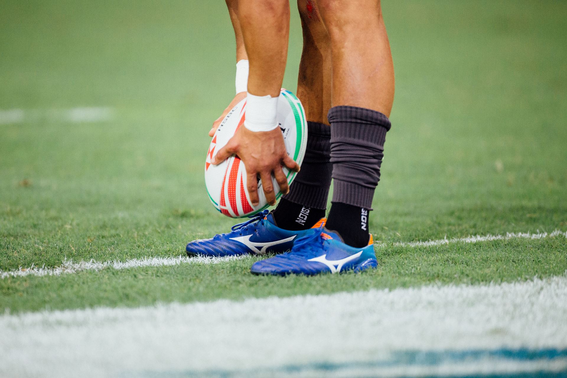 An image of a rugby player from the knees down placing a rugby ball on the ground