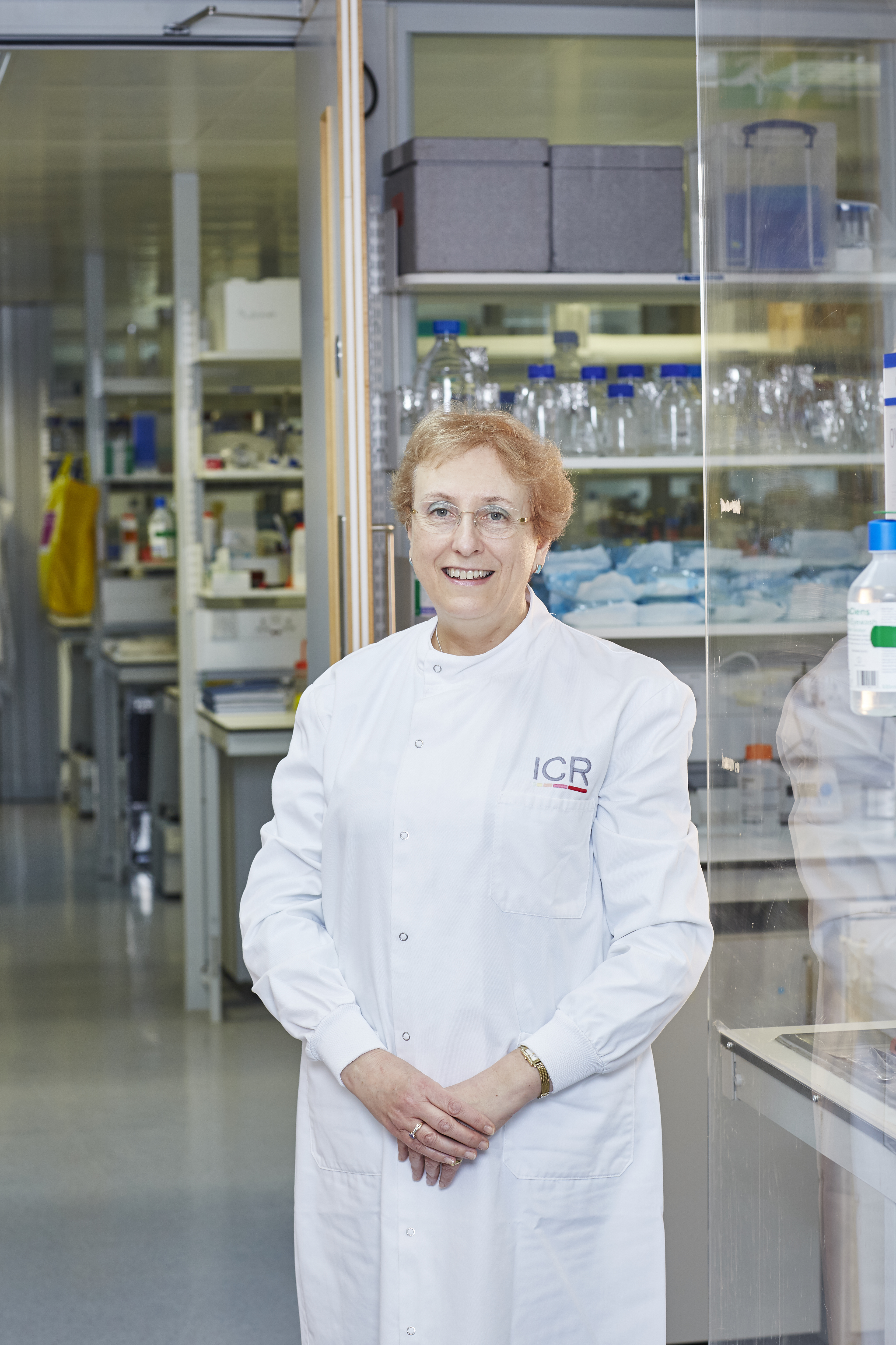 An image of a smiling Professor Ros Eeles, looking directly at the camera, wearing an ICR labcoat in a lab