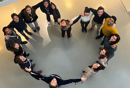 Researchers standing holding hands forming a heart shape, photo taken from above