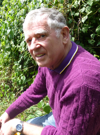 An image of Professor Stephen Bown, wearing a purple jumper, crouching next to a plant