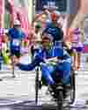 Assisted wheelchair participant passes the finish line of the Milano Marathon.