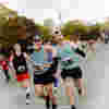 Runners point and smile at the camera as they run the Toronto Half Marathon.