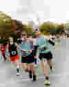 Runners point and smile at the camera as they run the Toronto Half Marathon.
