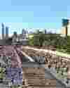 Runners in the Chicago Marathon run towards the camera with the Chicago skyline in the background.