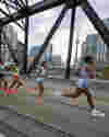 Runners in Toronto Marathon cross a bridge with Toronto skyline in the background.