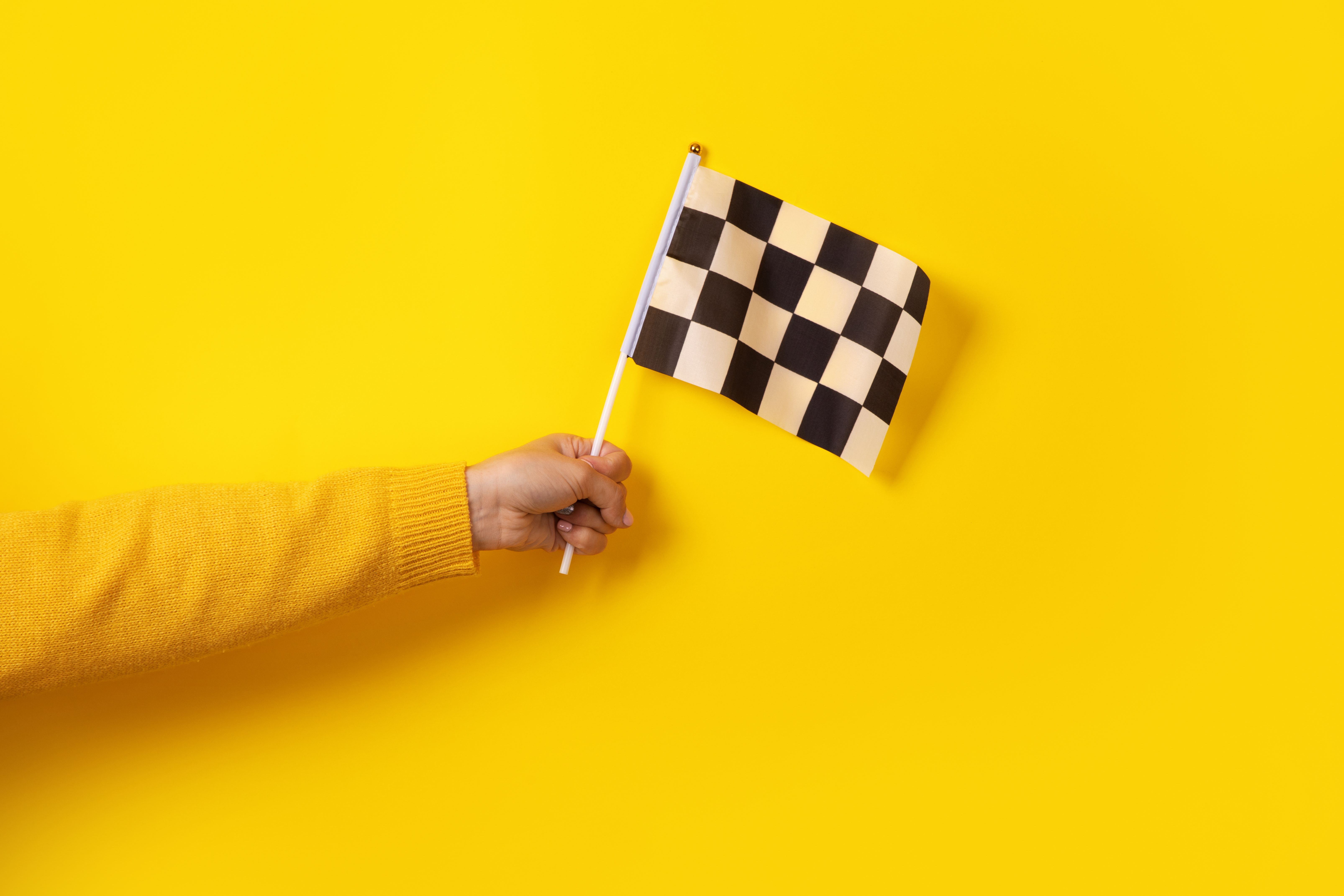 A hand holding a chequered flag
