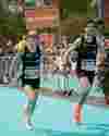 Three runners in the Vienna Marathon approach the finish line holding hands.