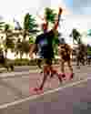 Runners in the Miami Marathon running on a palm-tree lined street.